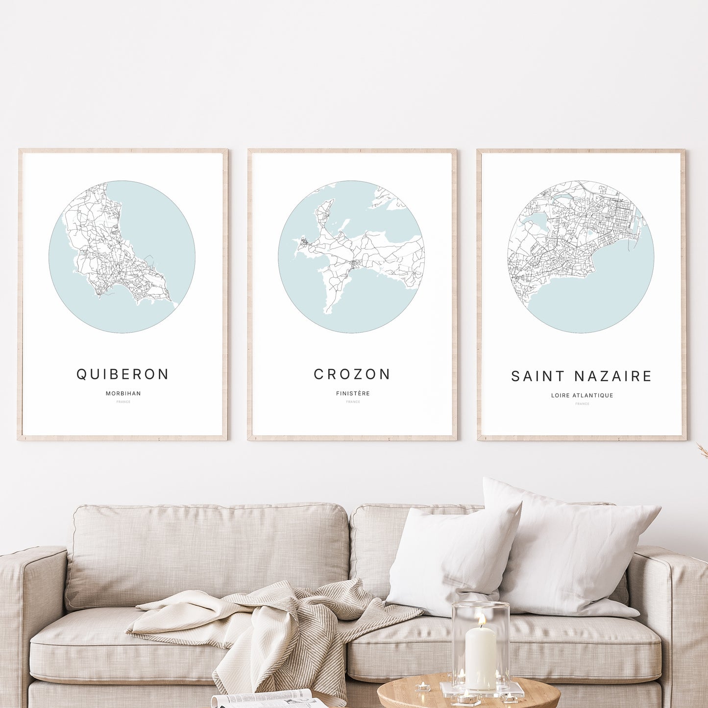 Composition murale de trois affiches minimalistes de villes (Crozon, Quiberon, Saint-Nazaire) encadrées au-dessus d’un canapé dans un salon moderne.