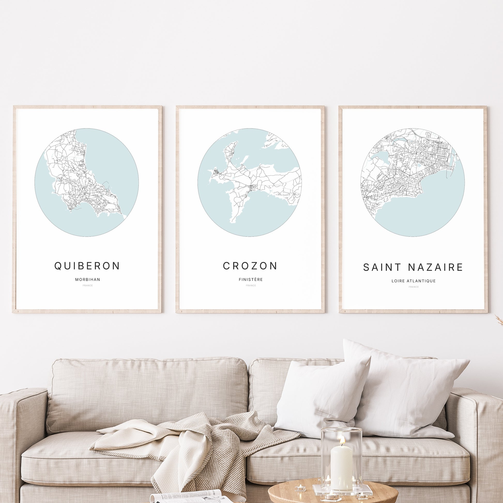 Composition murale de trois affiches minimalistes de villes (Crozon, Quiberon, Saint-Nazaire) encadrées au-dessus d’un canapé dans un salon moderne.