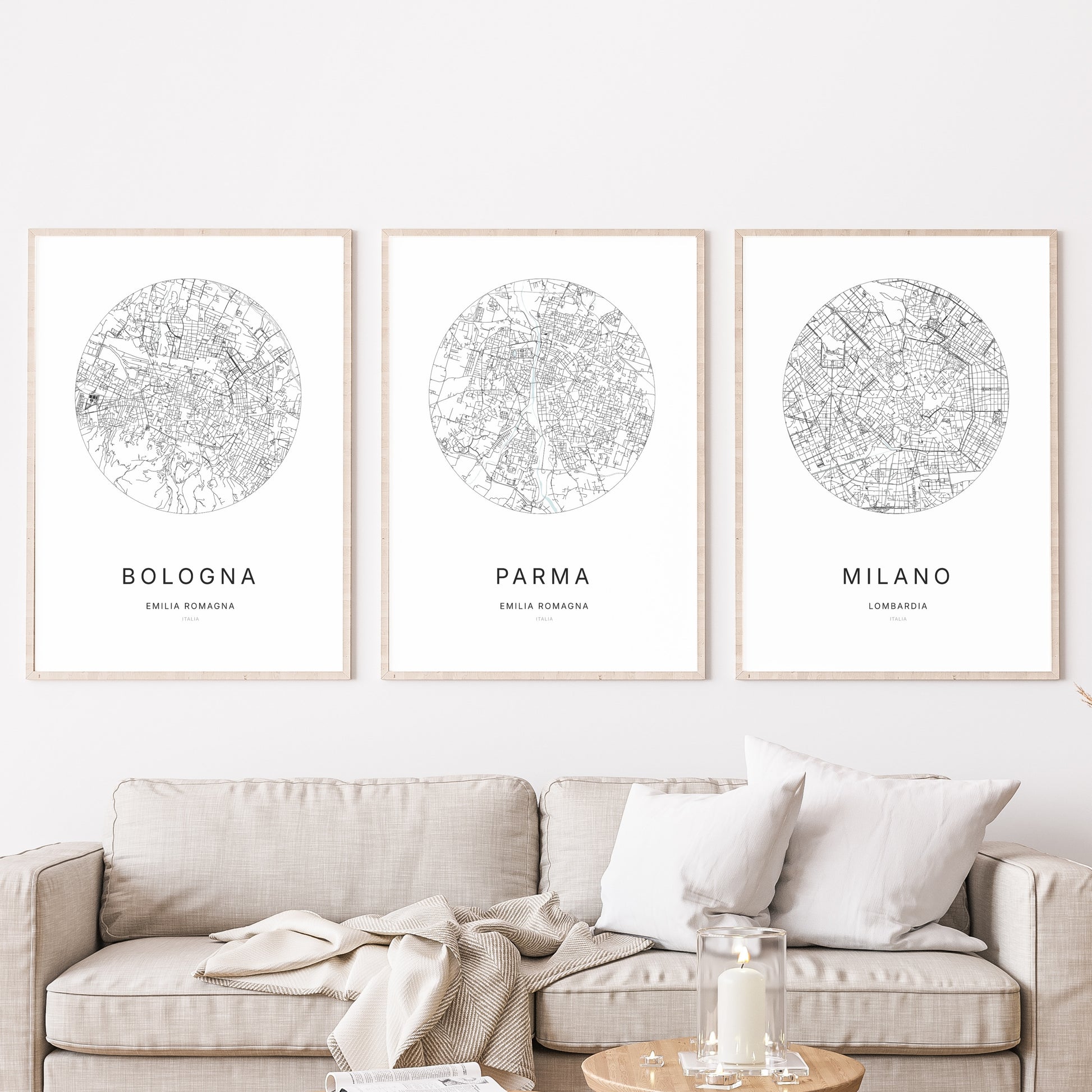 Composition murale de trois affiches minimalistes de villes (Parma, Bologna, Milano) encadrées au-dessus d’un canapé dans un salon moderne.