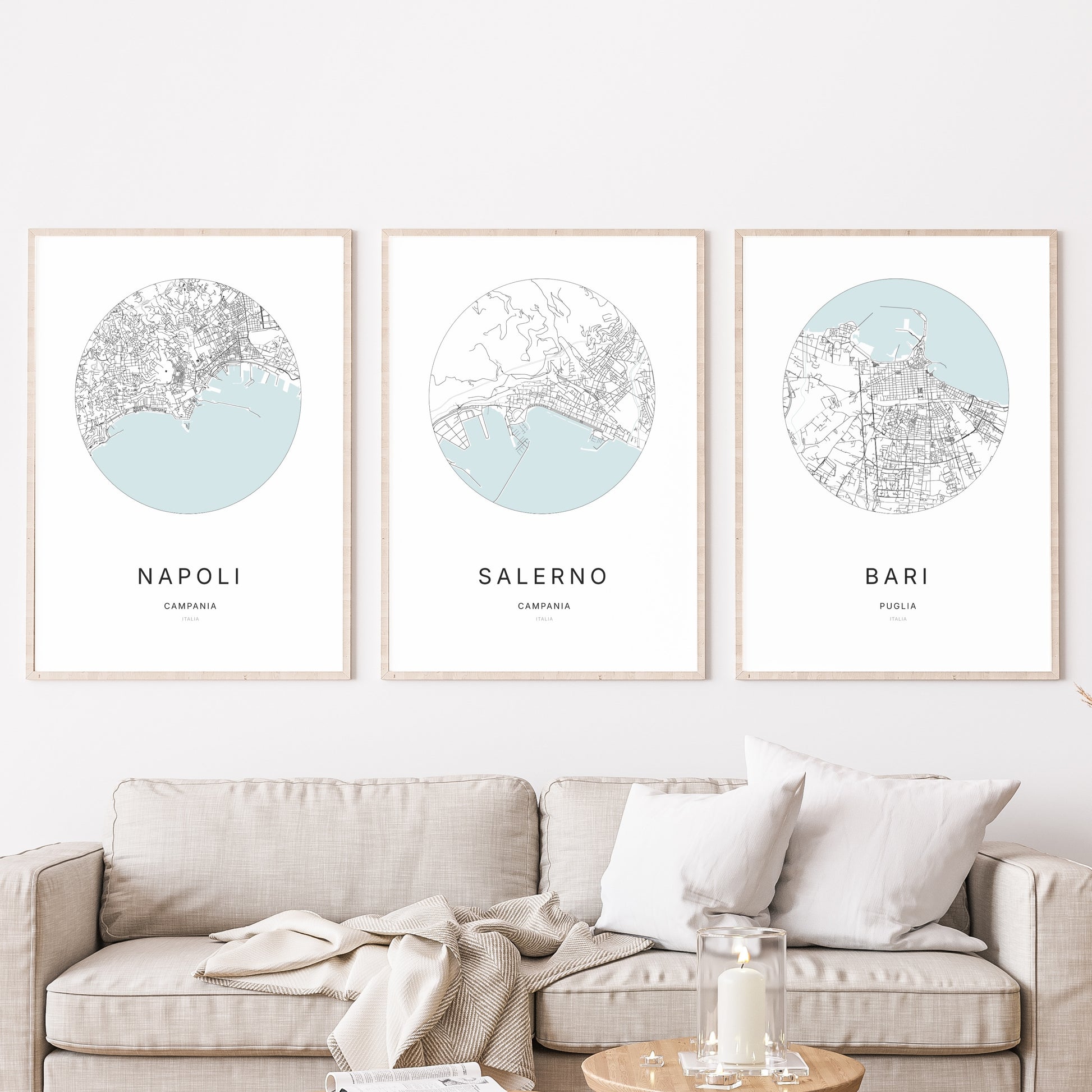 Composition murale de trois affiches minimalistes de villes (Salerno, Napoli, Bari) encadrées au-dessus d’un canapé dans un salon moderne.