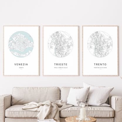 Composition murale de trois affiches minimalistes de villes (Trieste, Venezia, Trento) encadrées au-dessus d’un canapé dans un salon moderne.