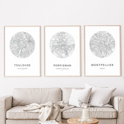 Composition murale de trois affiches minimalistes de villes (Perpignan, Montpellier, Toulouse) encadrées au-dessus d’un canapé dans un salon moderne