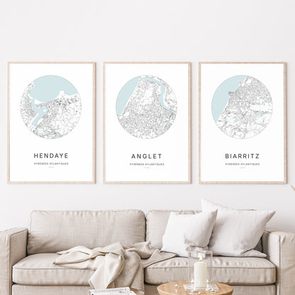 Composition murale de trois affiches minimalistes de villes (Anglet, Hendaye, Biarritz) encadrées au-dessus d’un canapé dans un salon moderne.