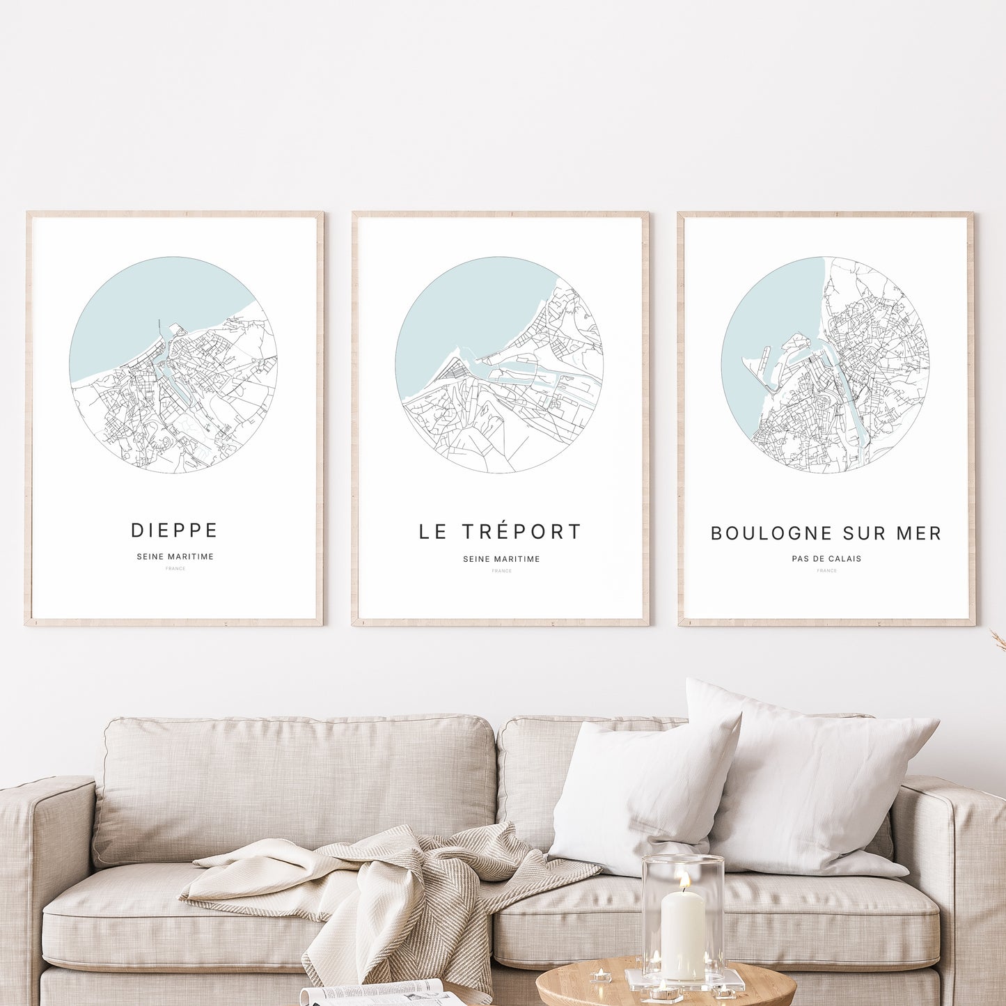 Composition murale de trois affiches minimalistes de villes (Le Tréport, Dieppe, Boulogne-sur-Mer) encadrées au-dessus d’un canapé dans un salon moderne. 