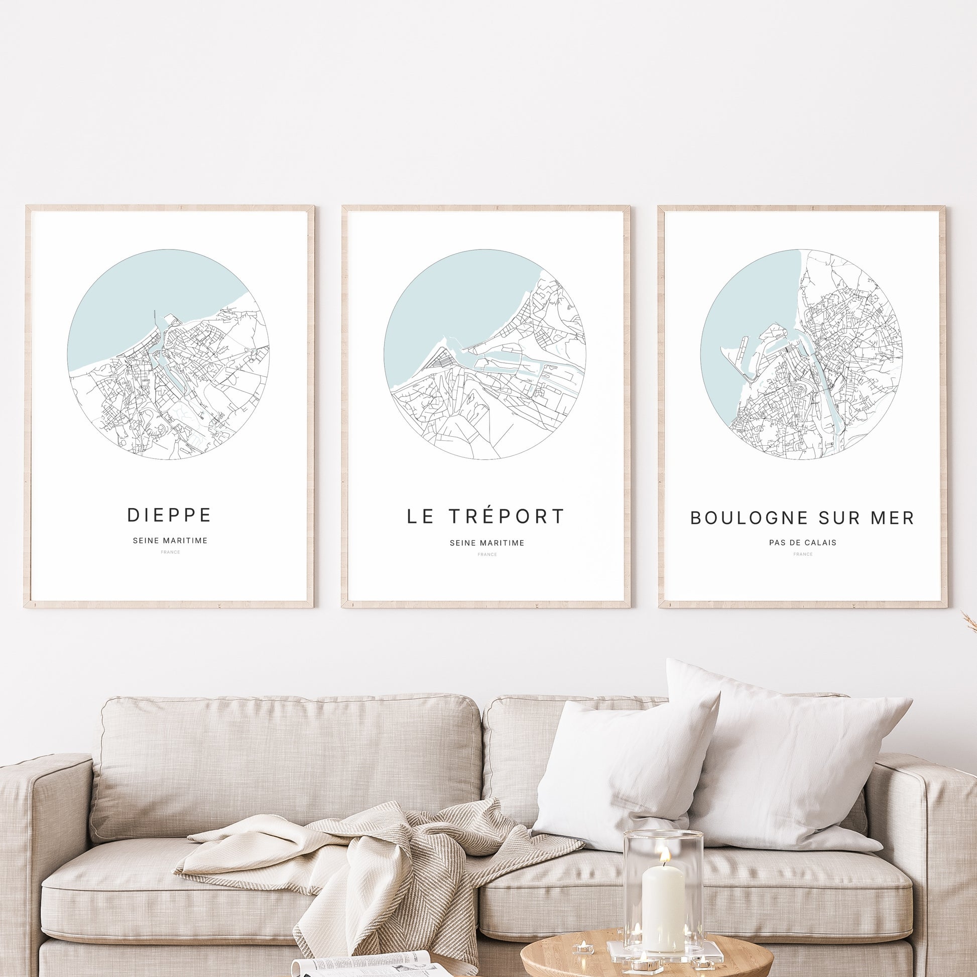 Composition murale de trois affiches minimalistes de villes (Le Tréport, Dieppe, Boulogne-sur-Mer) encadrées au-dessus d’un canapé dans un salon moderne. 
