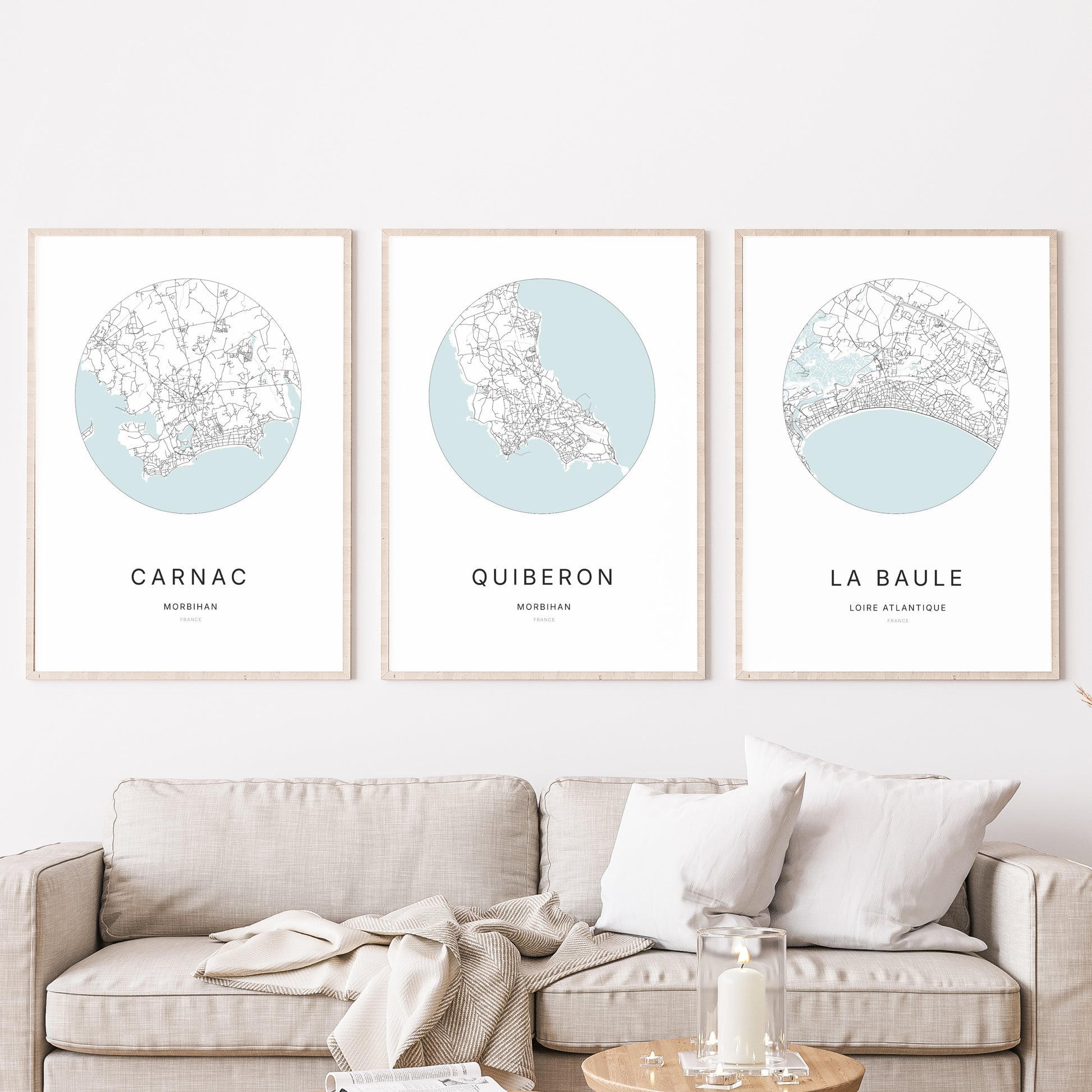 Composition murale de trois affiches minimalistes de villes (Quiberon, Carnac, La Baule) encadrées au-dessus d’un canapé dans un salon moderne.