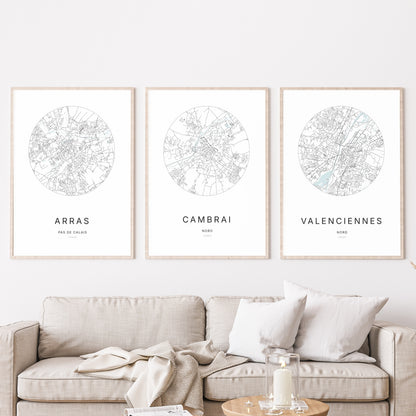 Composition murale de trois affiches minimalistes de villes (Cambrai, Arras, Valenciennes) encadrées au-dessus d’un canapé dans un salon moderne.