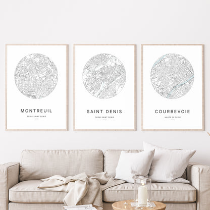 Composition murale de trois affiches minimalistes de villes (Saint-Denis, Montreuil, Courbevoie) encadrées au-dessus d’un canapé dans un salon moderne.