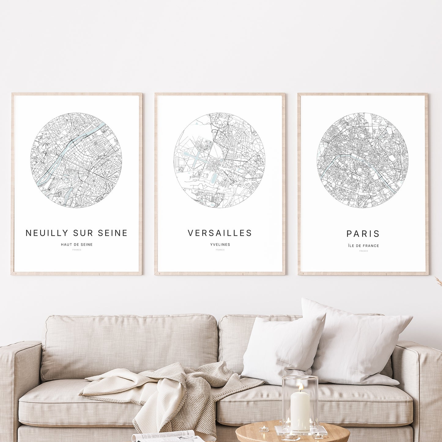 Composition murale de trois affiches minimalistes de villes (Versailles, Paris, Neuilly-sur-Seine) encadrées au-dessus d’un canapé dans un salon moderne