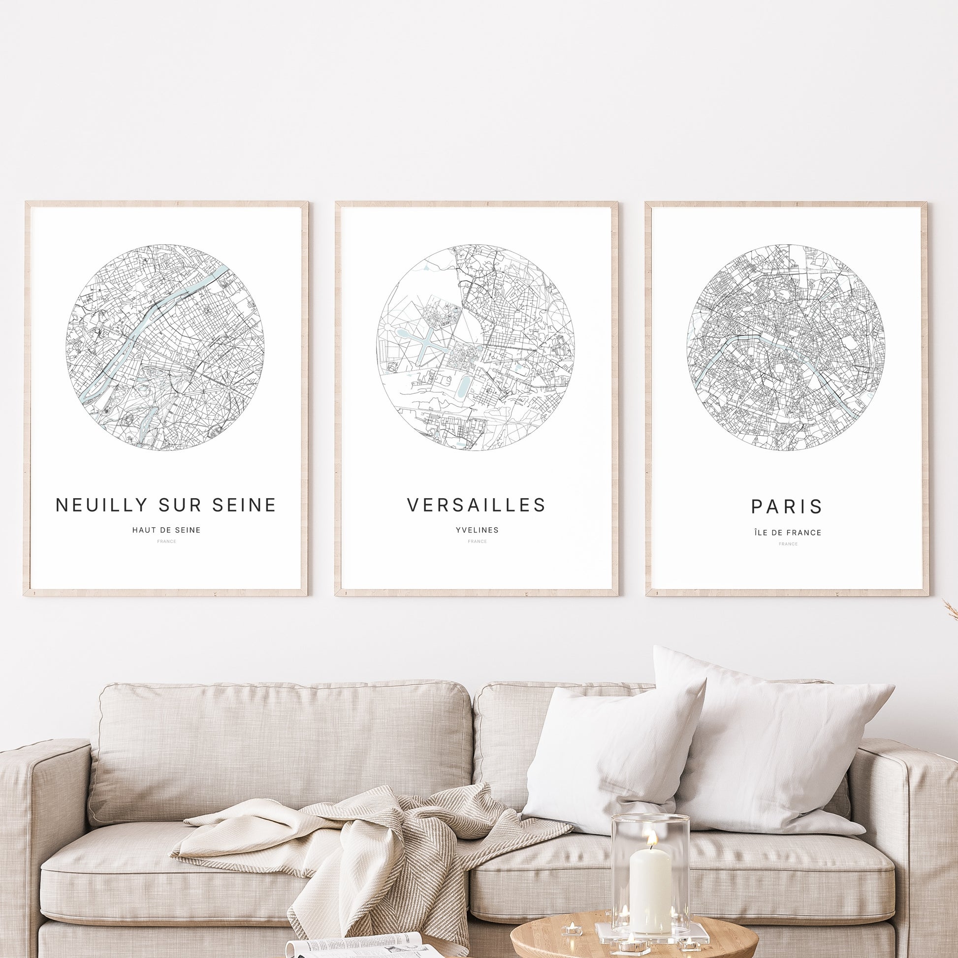 Composition murale de trois affiches minimalistes de villes (Versailles, Paris, Neuilly-sur-Seine) encadrées au-dessus d’un canapé dans un salon moderne