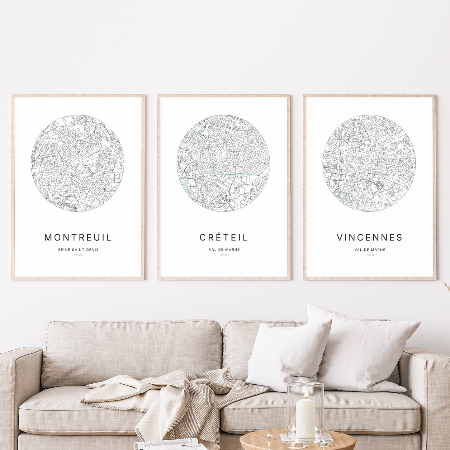 Composition murale de trois affiches minimalistes de villes (Créteil, Montreuil, Vincennes) encadrées au-dessus d’un canapé dans un salon moderne.