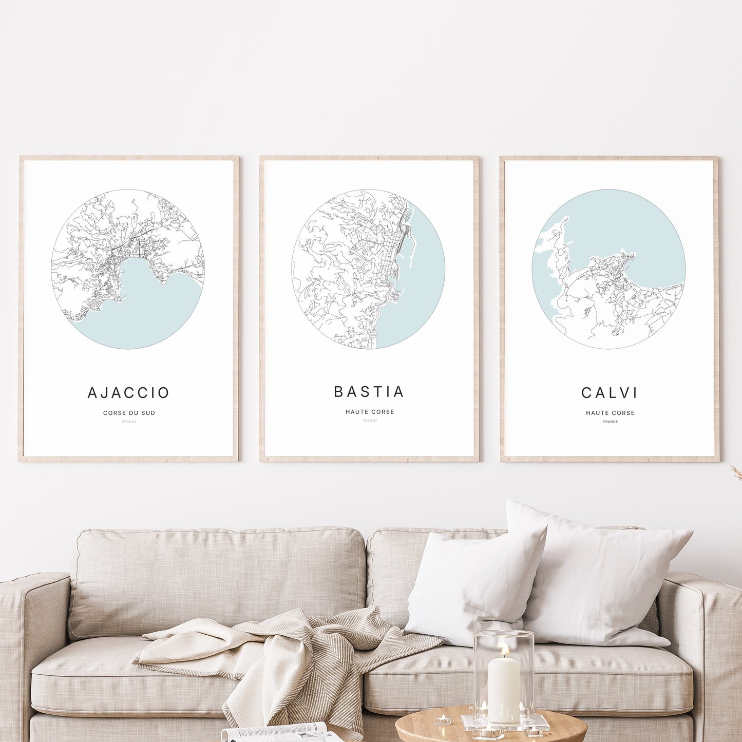 Composition murale de trois affiches minimalistes de villes (Bastia, Ajaccio, Calvi) encadrées au-dessus d’un canapé dans un salon moderne.