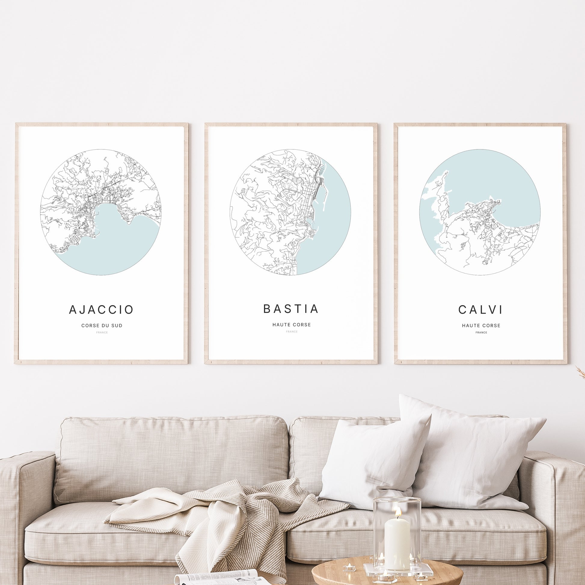 Composition murale de trois affiches minimalistes de villes (Bastia, Ajaccio, Calvi) encadrées au-dessus d’un canapé dans un salon moderne.
