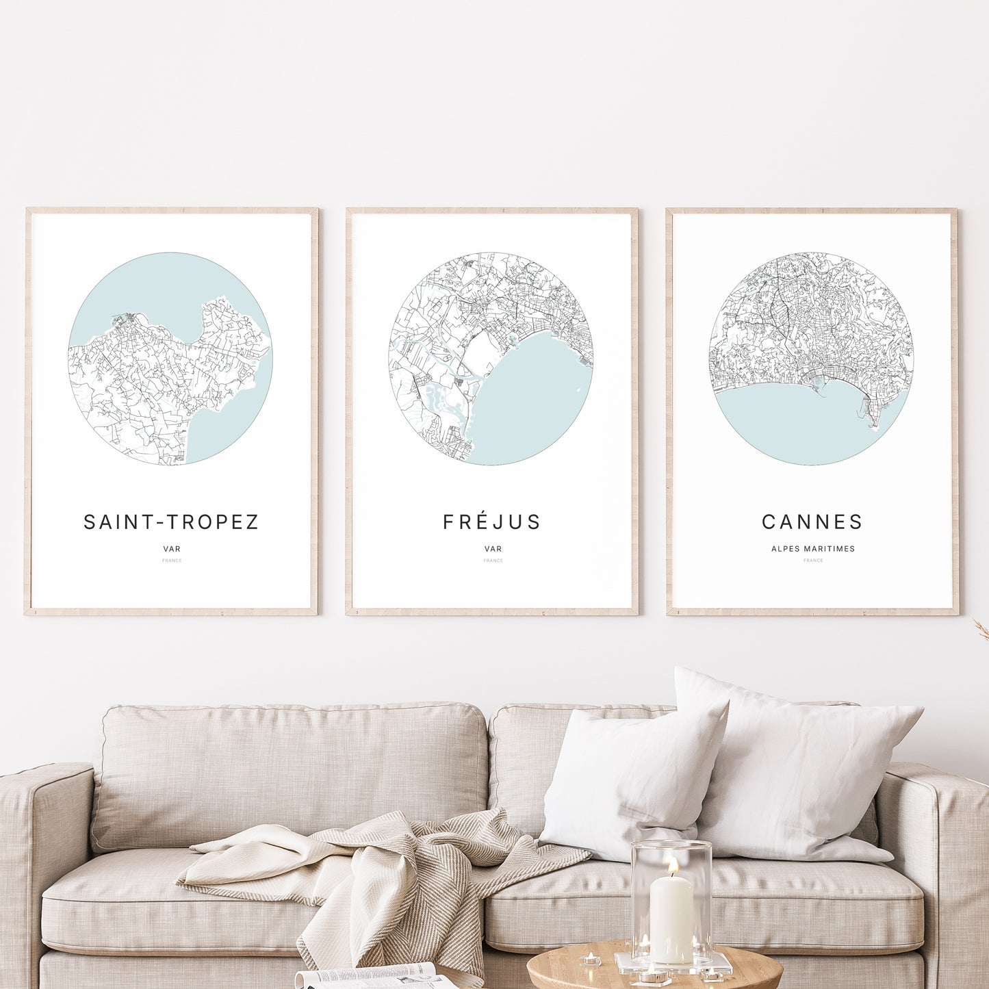 Composition murale de trois affiches minimalistes de villes (Fréjus, Saint-Tropez, Cannes) encadrées au-dessus d’un canapé dans un salon moderne.