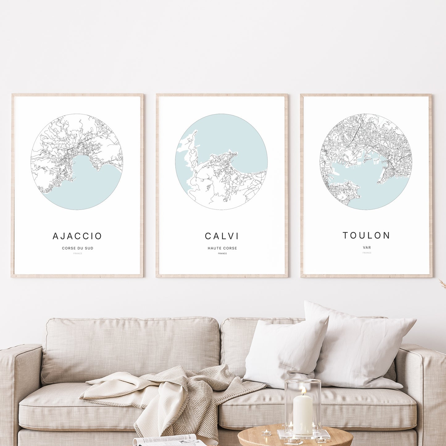 Composition murale de trois affiches minimalistes de villes (Calvi, Ajaccio, Toulon) encadrées au-dessus d’un canapé dans un salon moderne