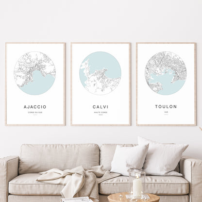 Composition murale de trois affiches minimalistes de villes (Calvi, Ajaccio, Toulon) encadrées au-dessus d’un canapé dans un salon moderne