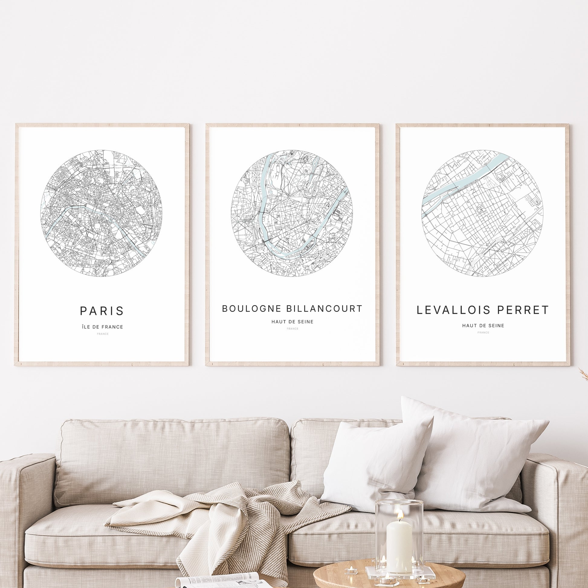 Composition murale de trois affiches minimalistes de villes (Boulogne-Billancourt, Paris, Levallois-Perret) encadrées au-dessus d’un canapé dans un salon moderne.