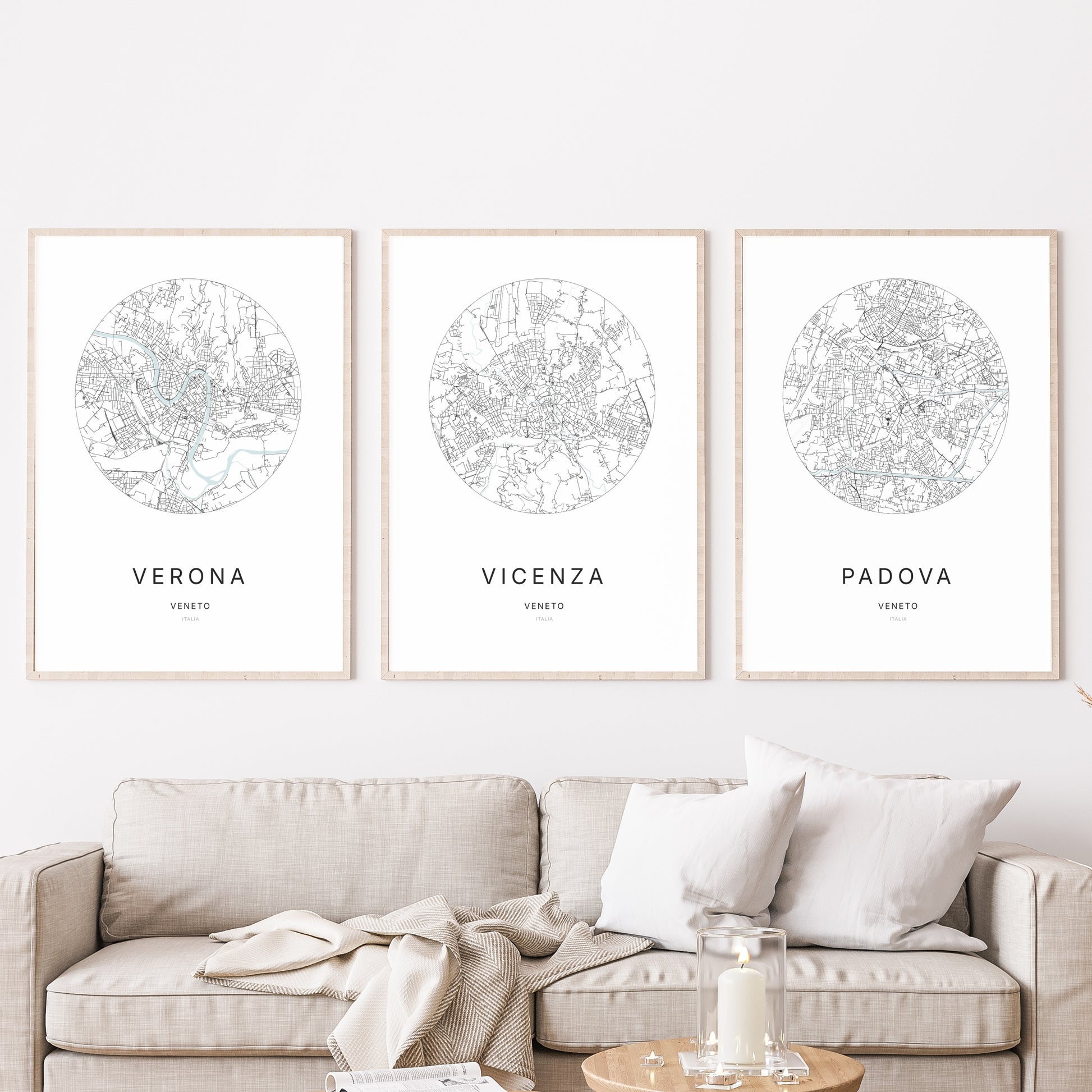 Composition murale de trois affiches minimalistes de villes (Vicenza, Verona, Padova) encadrées au-dessus d’un canapé dans un salon moderne.