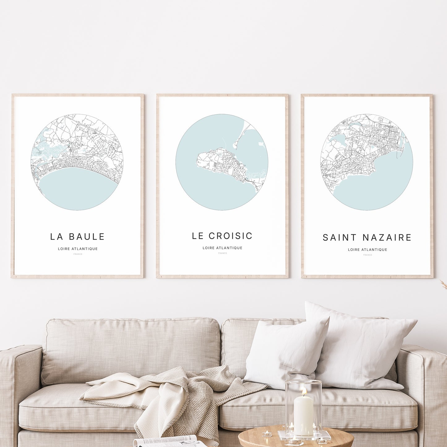 Composition murale de trois affiches minimalistes de villes (Le Croisic, La Baule, Saint-Nazaire) encadrées au-dessus d’un canapé dans un salon moderne.