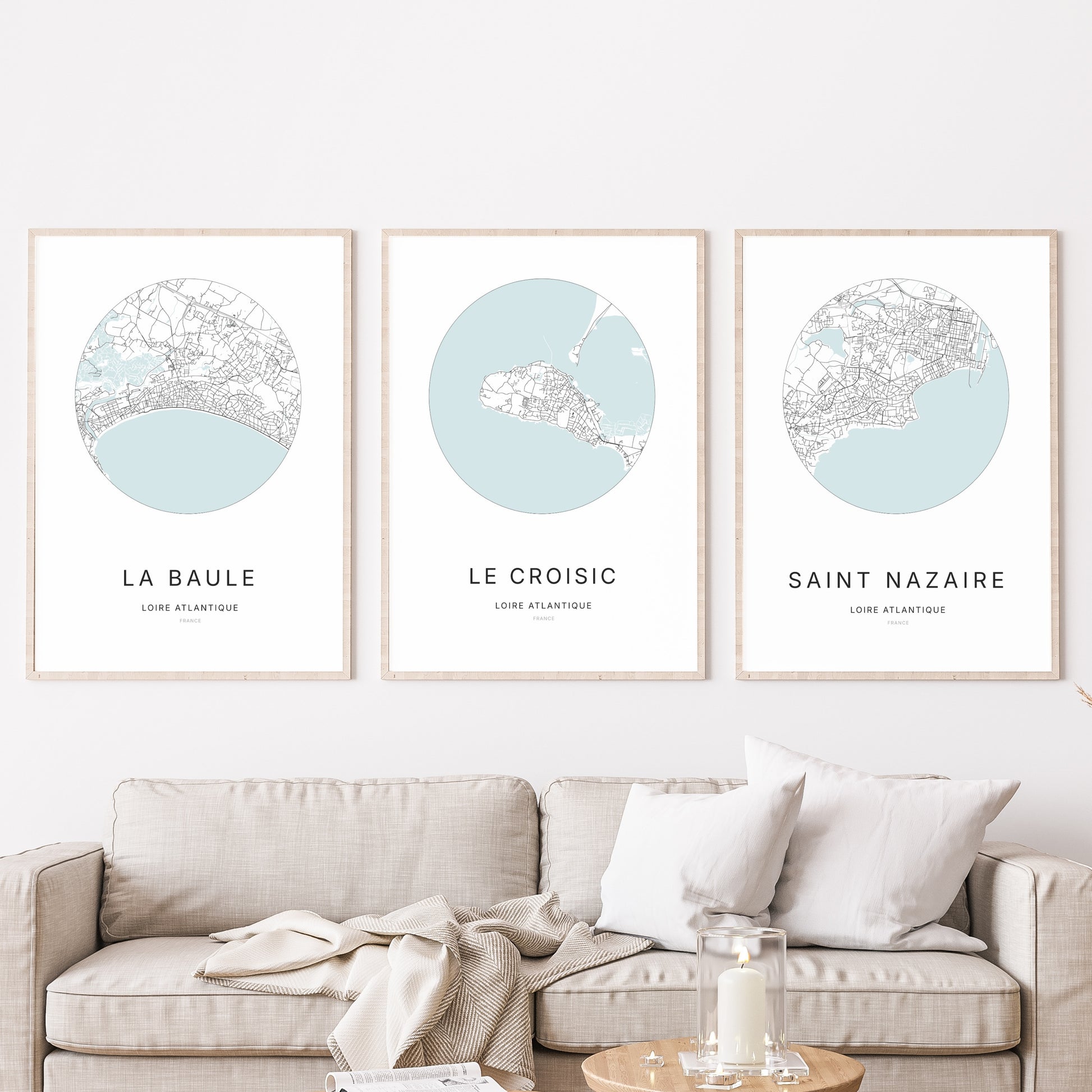 Composition murale de trois affiches minimalistes de villes (Le Croisic, La Baule, Saint-Nazaire) encadrées au-dessus d’un canapé dans un salon moderne.