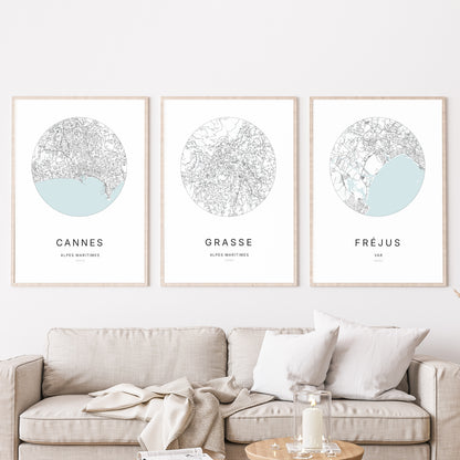 Composition murale de trois affiches minimalistes de villes (Grasse, Cannes, Fréjus) encadrées au-dessus d’un canapé dans un salon moderne.