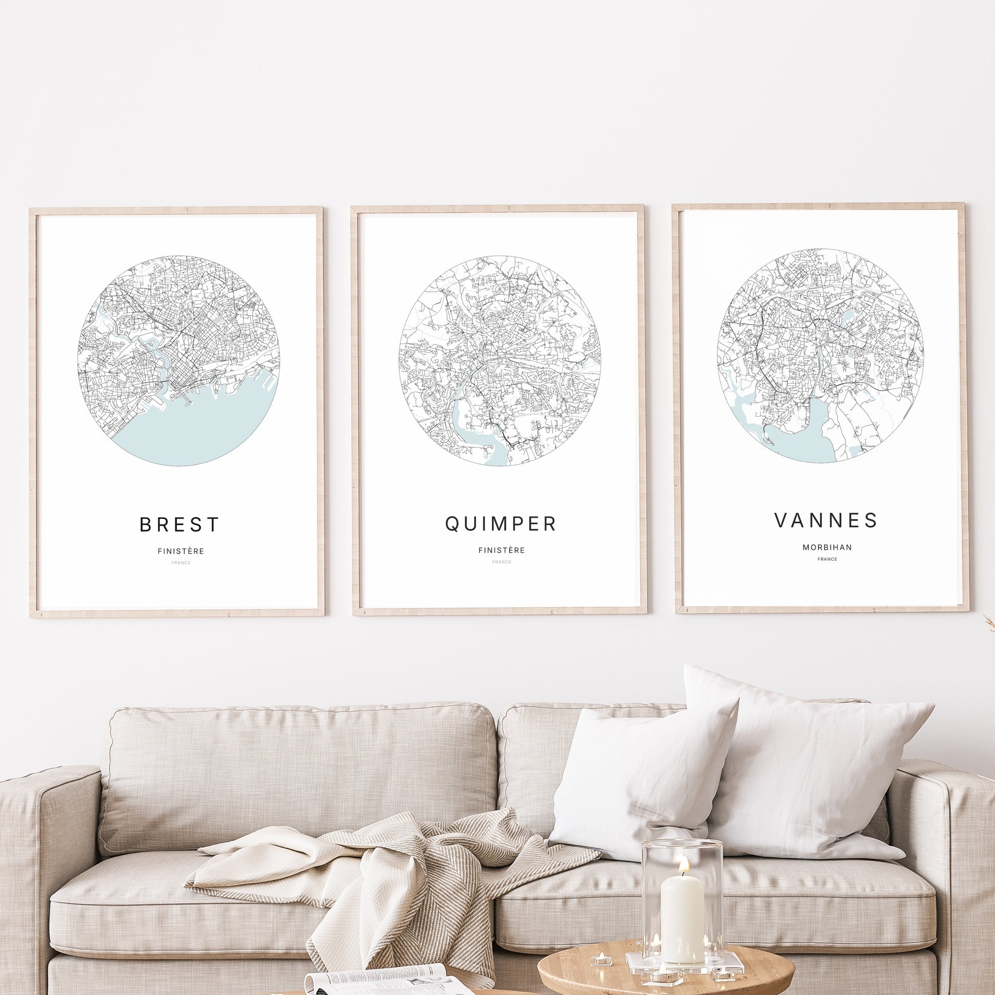 Composition murale de trois affiches minimalistes de villes (Quimper, Vannes, Brest) encadrées au-dessus d’un canapé dans un salon moderne