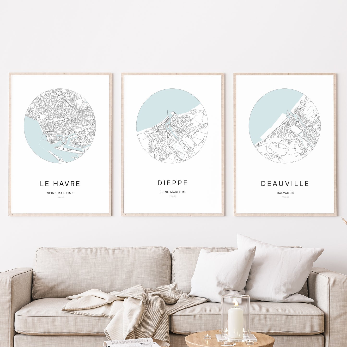 Composition murale de trois affiches minimalistes de villes (Dieppe, Le Havre, Deauville) encadrées au-dessus d’un canapé dans un salon moderne.