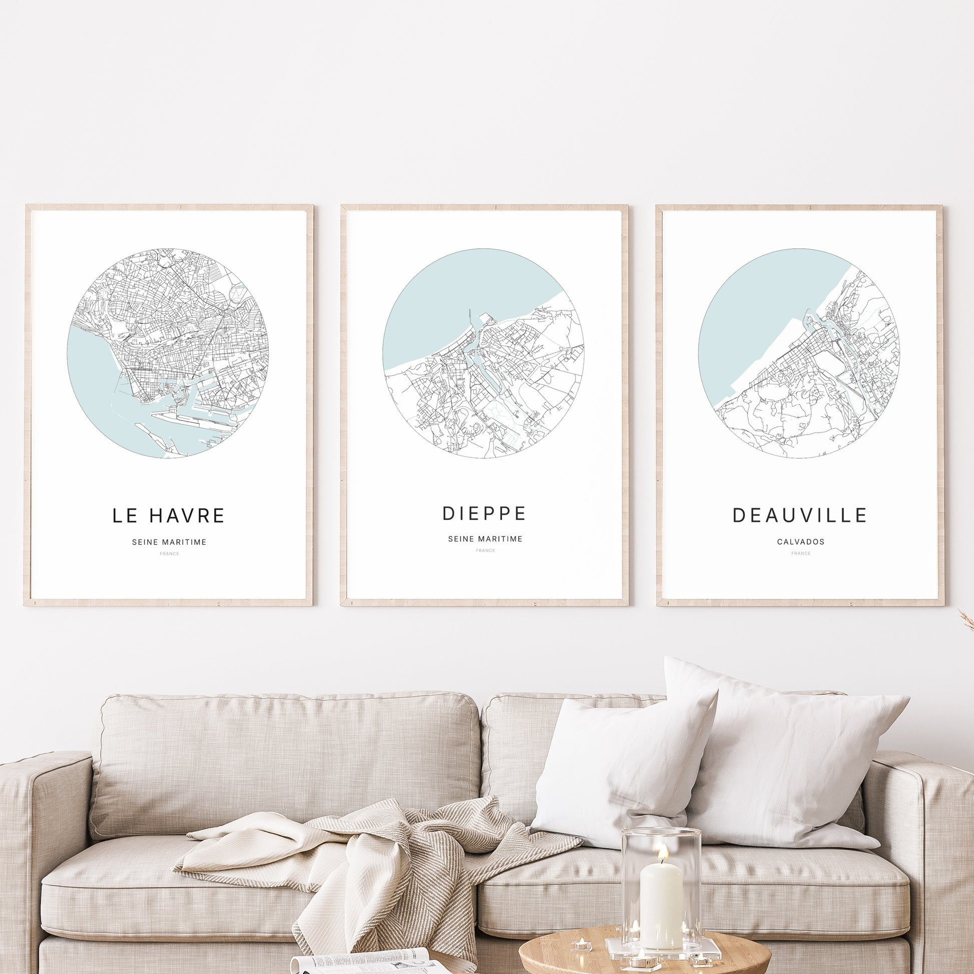 Composition murale de trois affiches minimalistes de villes (Dieppe, Le Havre, Deauville) encadrées au-dessus d’un canapé dans un salon moderne.