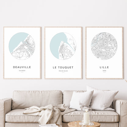 Composition murale de trois affiches minimalistes de villes (Le Touquet, Deauville, Lille) encadrées au-dessus d’un canapé dans un salon moderne.