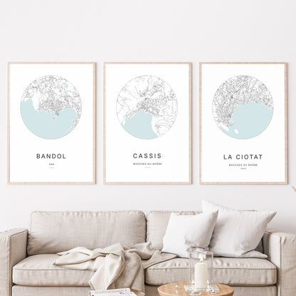 Composition murale de trois affiches minimalistes de villes (Cassis, Bandol, La Ciotat) encadrées au-dessus d’un canapé dans un salon moderne.