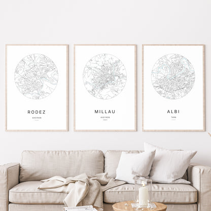 Composition murale de trois affiches minimalistes de villes (Millau, Rodez, Albi) encadrées au-dessus d’un canapé dans un salon moderne.