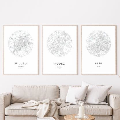Composition murale de trois affiches minimalistes de villes (Rodez, Millau, Albi) encadrées au-dessus d’un canapé dans un salon moderne.