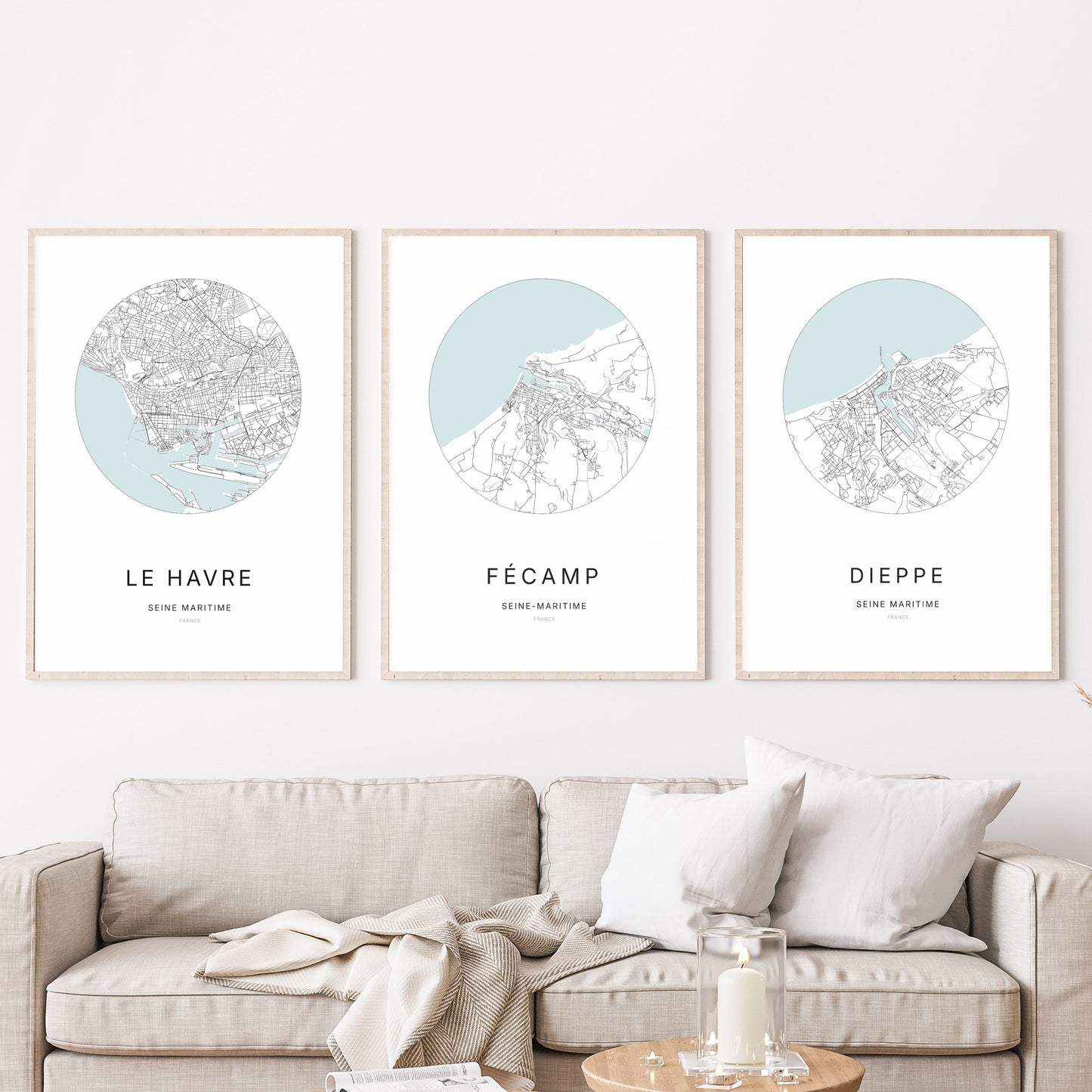 Composition murale de trois affiches minimalistes de villes (Fécamp, Le Havre, Dieppe) encadrées au-dessus d’un canapé dans un salon moderne.