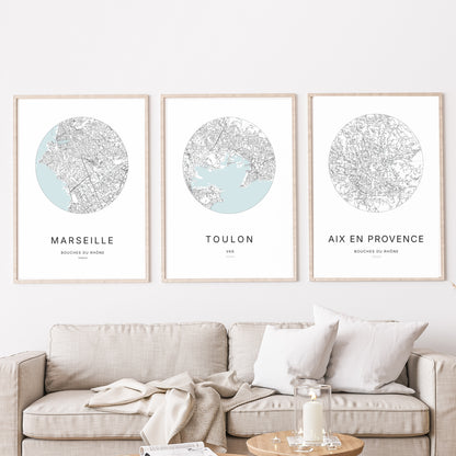 Composition murale de trois affiches minimalistes de villes (Marseille, Toulon, Aix-en-Provence) encadrées au-dessus d’un canapé dans un salon moderne