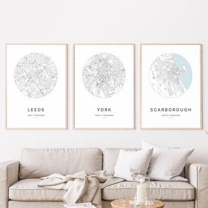 Trio of Leeds, York and Scarborough city map prints in a living room.