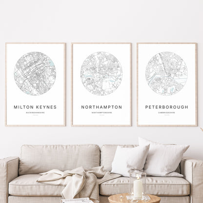 Trio of Milton Keynes, Northampton and Peterborough city map prints in a living room.
