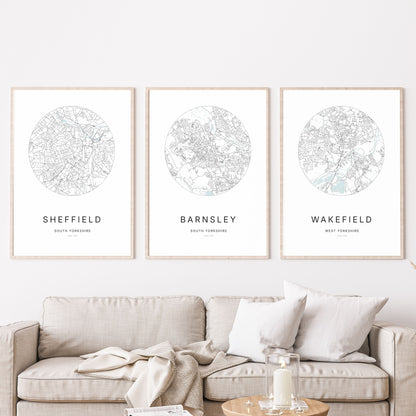 Trio of Sheffield, Barnsley and Wakefield city map prints in a living room.