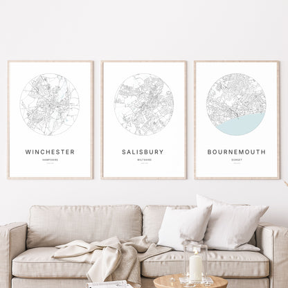 Trio of Winchester, Salisbury and Bournemouth city map prints in a living room.